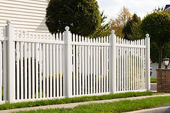 A new white vinyl fence by a grass area with trees behind it green property modern.jpg