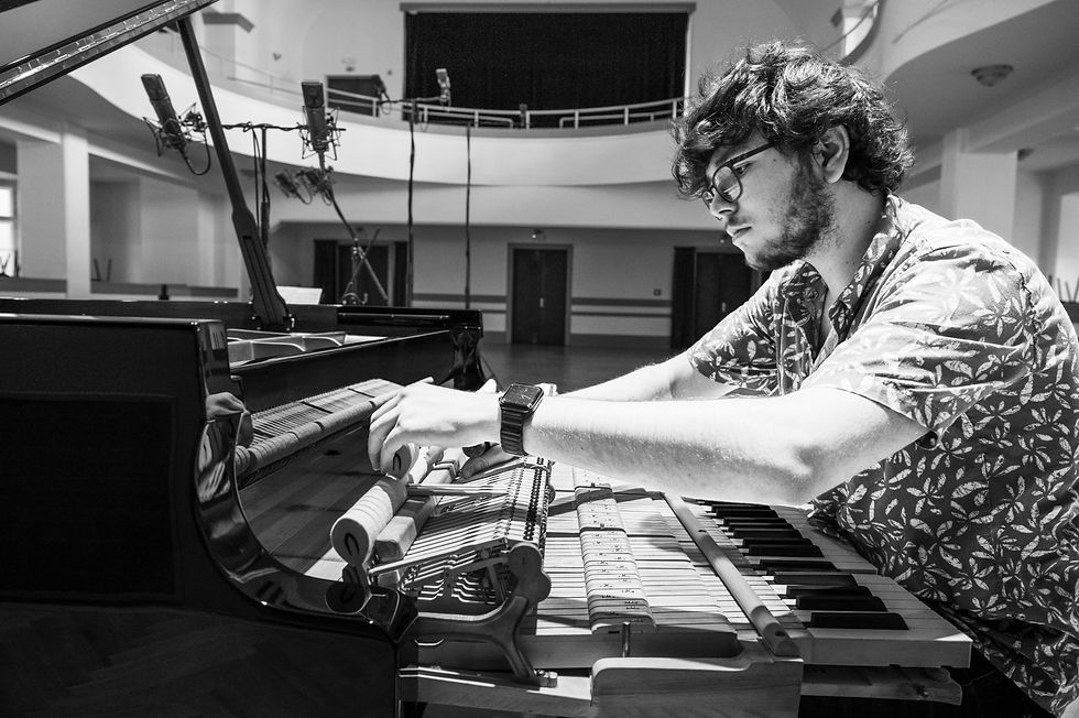 Filip Mareček bereitet einen Flügel für eine Tonaufnahme vor