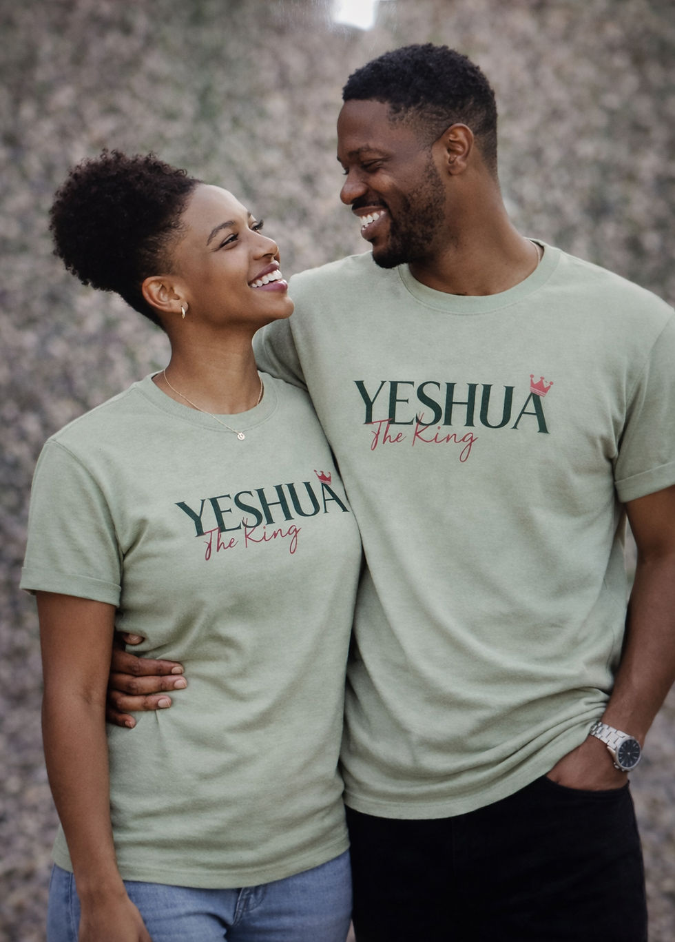 Couple wearing matching sage green christian t shirts with “yeshua the king” design