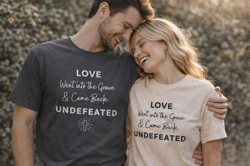 Smiling couple in charcoal and beige faith t-shirts featuring ‘Love Went Into the Grave and Came Back Undefeated’ resurrectio