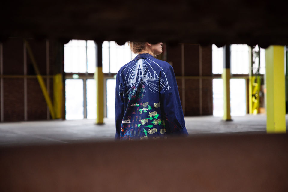 Look book shoot with blonde model in industrial hall, wearing a blue jacket with embroidery on it