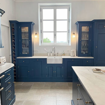 Cuisine aménagée avec armoires bleues, évier blanc, fenêtre ensoleillée. cuisine moderne Justkitchens