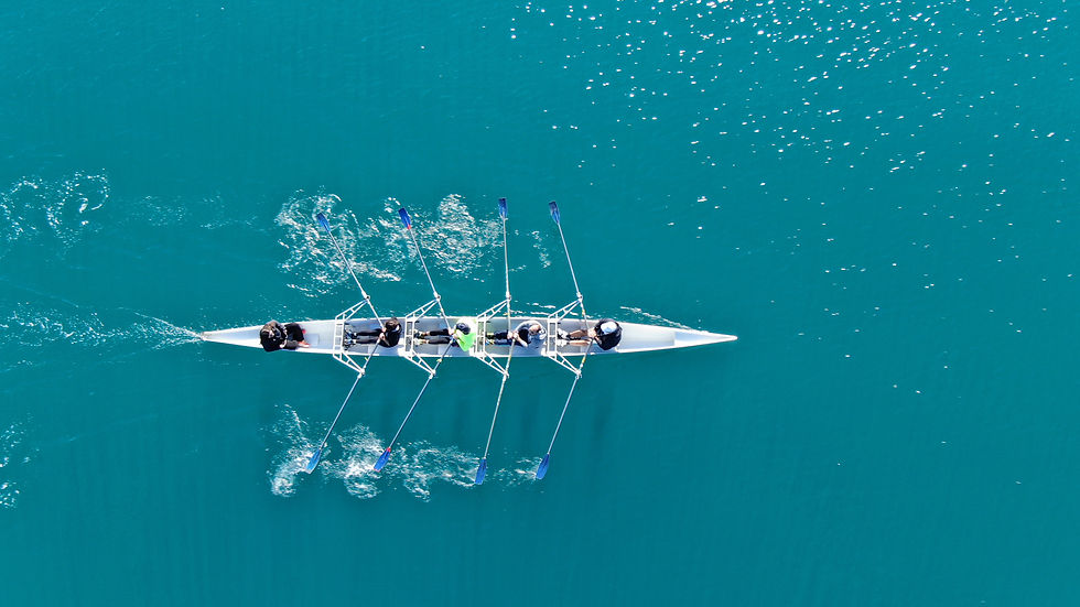 Aerial drone bird's eye view of sport canoe operated by team of young women in deep blue s