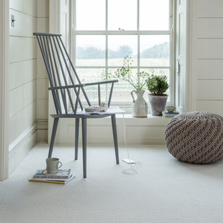 Wooden chair in front of big window.