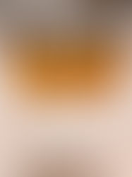 Three glass jars filled with amber liquid, black lids on, set on a beige countertop. A mosaic tile backsplash in browns and grays is visible. 