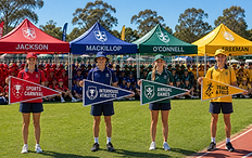 House captains holding custom event pennants in front of school sports carnival marquees