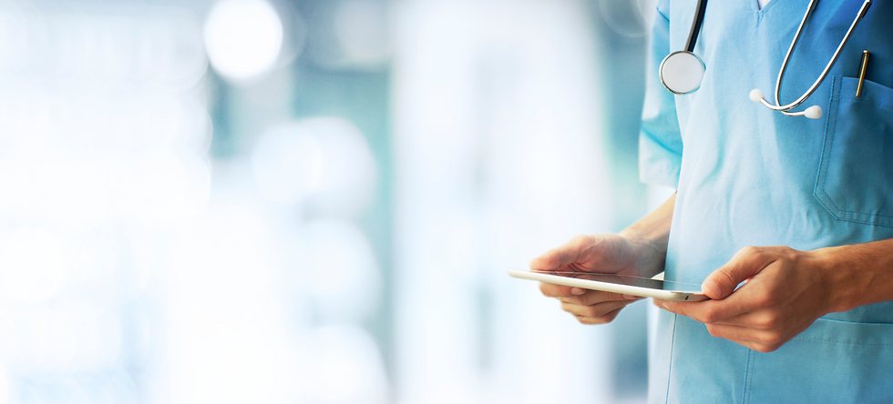 A healthcare professional in scrubs holds a tablet, with a stethoscope around their neck, standing in a bright medical environment.