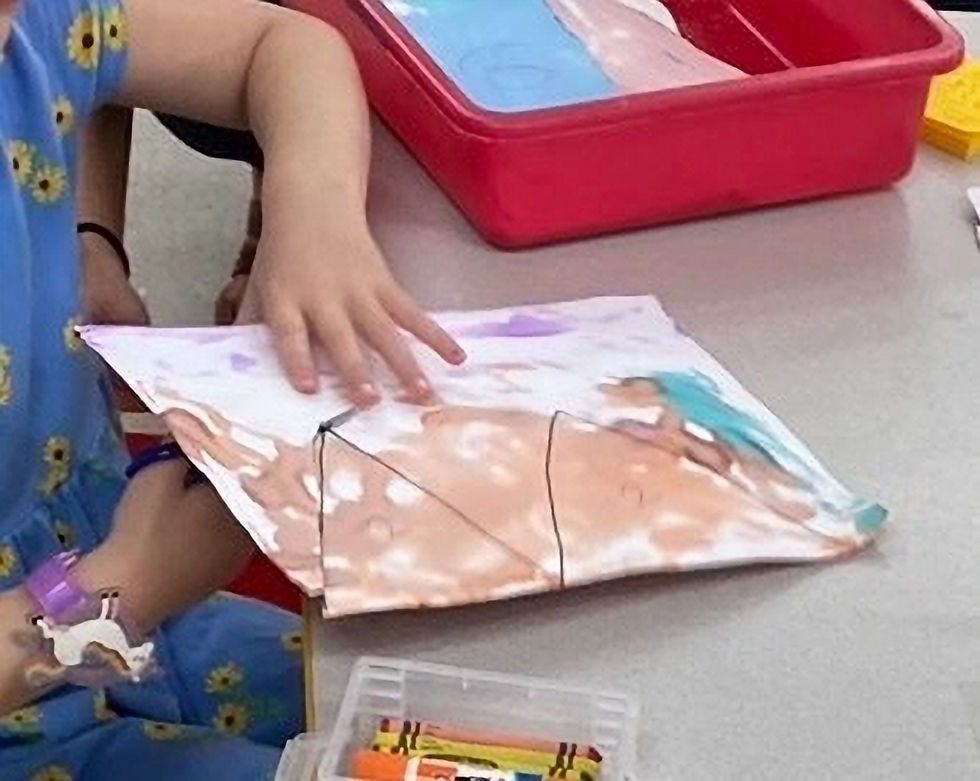 Preschool student practicing scissor skills by cutting painted paper shapes for a collaborative art activity.