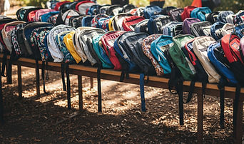 a large table outside full of donated book bags.jpg