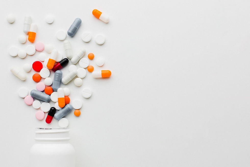Pills of various colors spill from a white bottle on a white background, including orange, grey, pink, and red capsules and tablets.