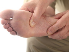 Hands massage the sole of a bare foot, set against a plain white background. The image conveys a sense of care and relaxation.