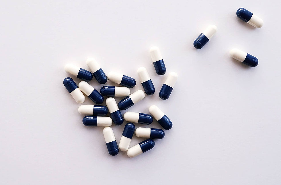 Blue and white capsules scattered on a white background, grouped mostly to the left. Mood is clinical and organized.