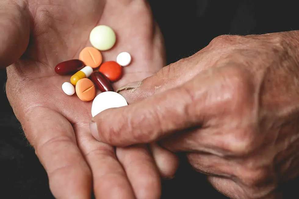 Hands holding various colorful pills. The background is dark, highlighting the colorful medication, suggesting a focus on healthcare or treatment.