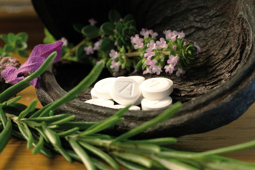 White tablets with imprints on a wooden surface, surrounded by purple flowers and green herbs, evoke a natural, calming mood.