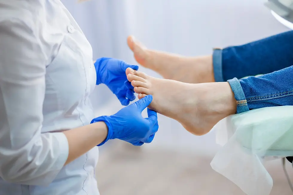 Person in white coat and blue gloves examines another's foot in jeans, set in a clinical environment. The mood is calm and professional.