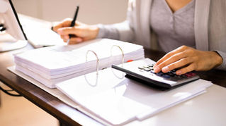 Person doing taxes wtih calculator and binder