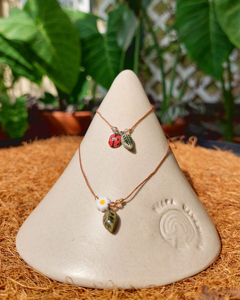 Collares de joyería botánica exhibidos en soporte de cerámica