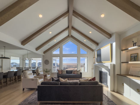 Living room with vaulted ceiling, wood beams, and scenic windows.