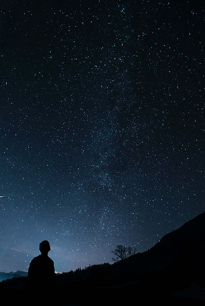 Foto von einem Mann, der nachts draußen steht und die Sterne betrachtet. Auf der Suche nach Antworten, Persönlichkeitsentwicklung, Lebensberatung, Führung, Lebensweg, astrologische Beratung.