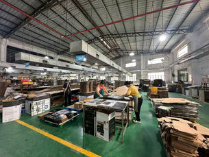 Workers handling printed sheets at tables in a packaging workshop