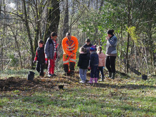 Un groupe d'enfants plante avec un agent communal