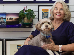 Owner of Armount and Framing Matters, Dixie Finlayson sits in a chair with her dog