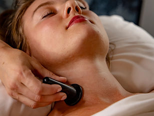 Practitioner using a cupping tool along a client’s neck during a rejuvenating acupuncture facial