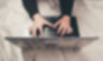 woman's hands typing on a black laptop keyboard