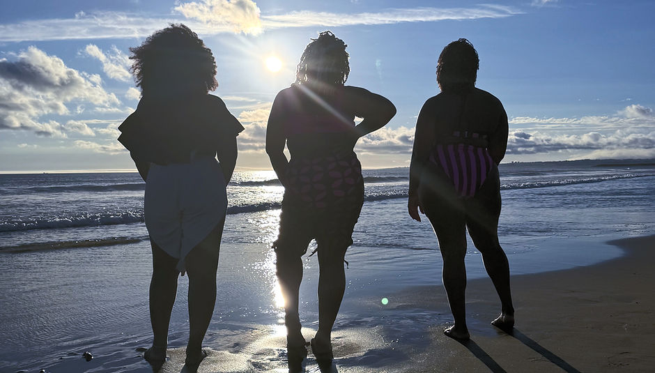 scenic view of beach with three african american women posing against the sun