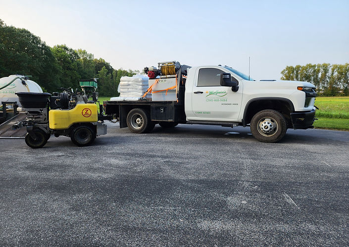 McGuin’s Solutions lawn care truck loaded with fertilizer and turf treatment supplies beside professional lawn application equipment.