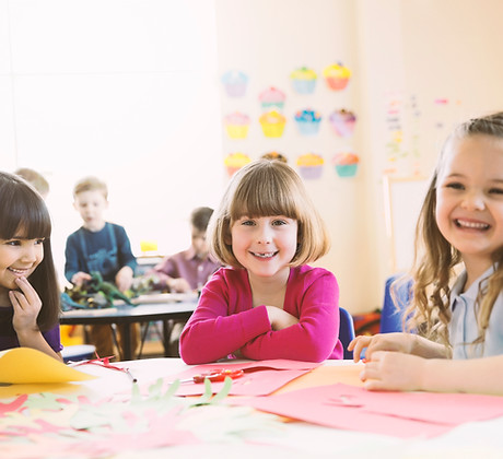 Smiling girls sitting at table in elementary class