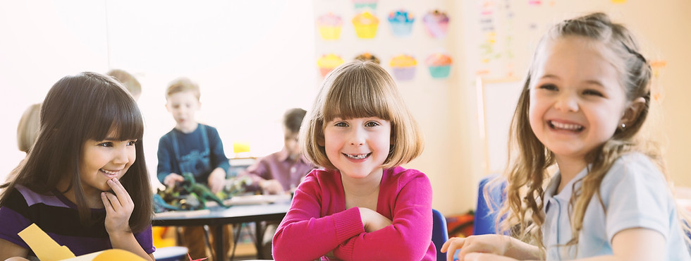 Lächelnde Mädchen am Tisch in der Grundklasse sitzen