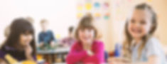 Smiling girls sitting at table in elementary class