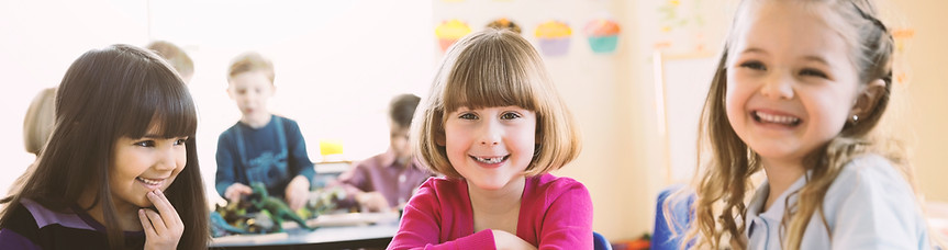 Smiling girls sitting at table in elemen