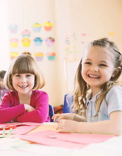 Smiling girls sitting at table in elemen