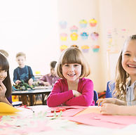 Smiling girls sitting at table in elemen