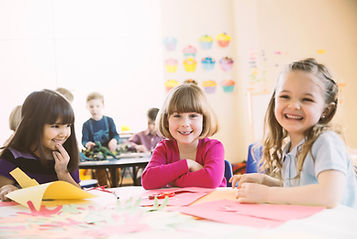 Smiling girls sitting at table in elementary class