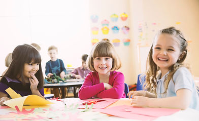 Smiling girls sitting at table in elementary class