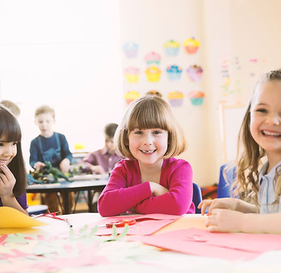 Niñas sonriendo sentado a la mesa en clase primaria