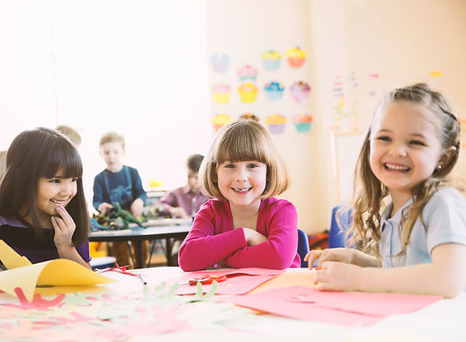 Smiling girls sitting at table in elemen