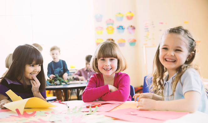 Smiling girls sitting at table in elementary class