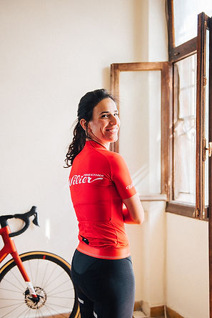 אישה לובשת חולצת רכיבה Wilier אדומה על רקע חלון פתוח