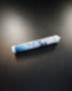 Zylindrischer Wasserfilter von Aquico, liegend auf einer dunklen, strukturierten Oberfläche. Das Gehäuse ist weiß-blau gestaltet, mit Wasserblasen-Design und Aquico-Logo. Ein Ende zeigt den Anschluss für die Installation.