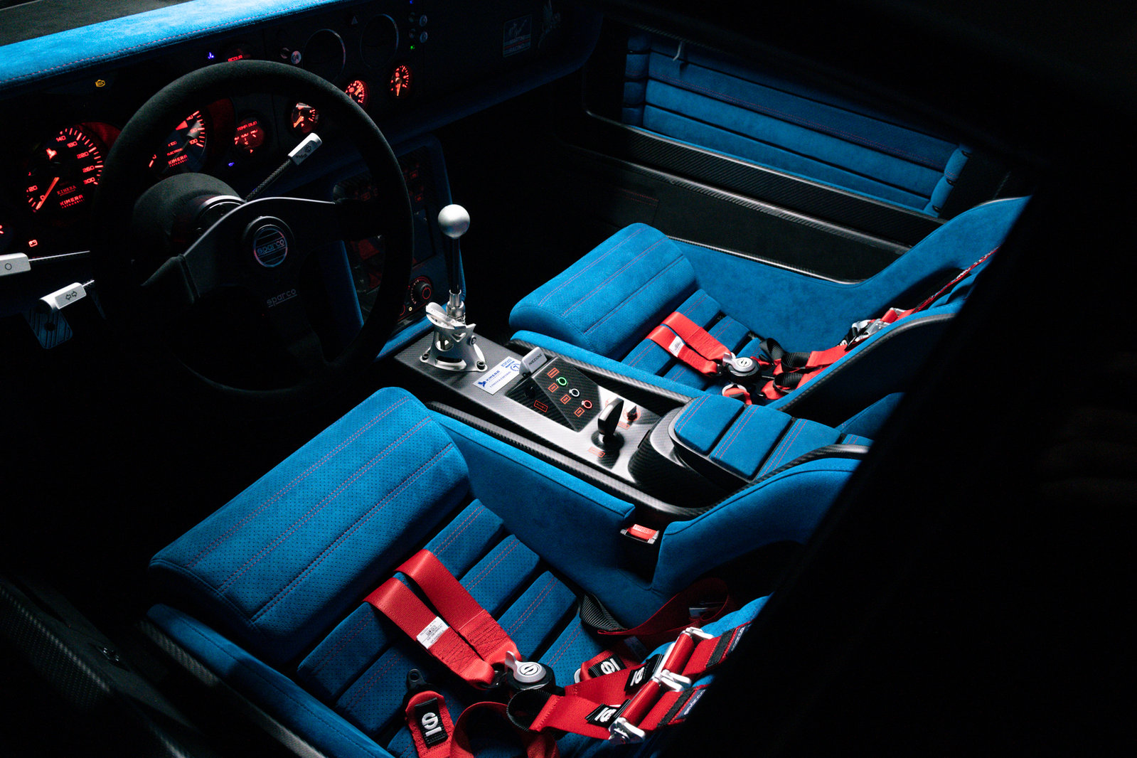 Kimera EVO37 interior with blue seats, red harnesses and exposed gear shifter