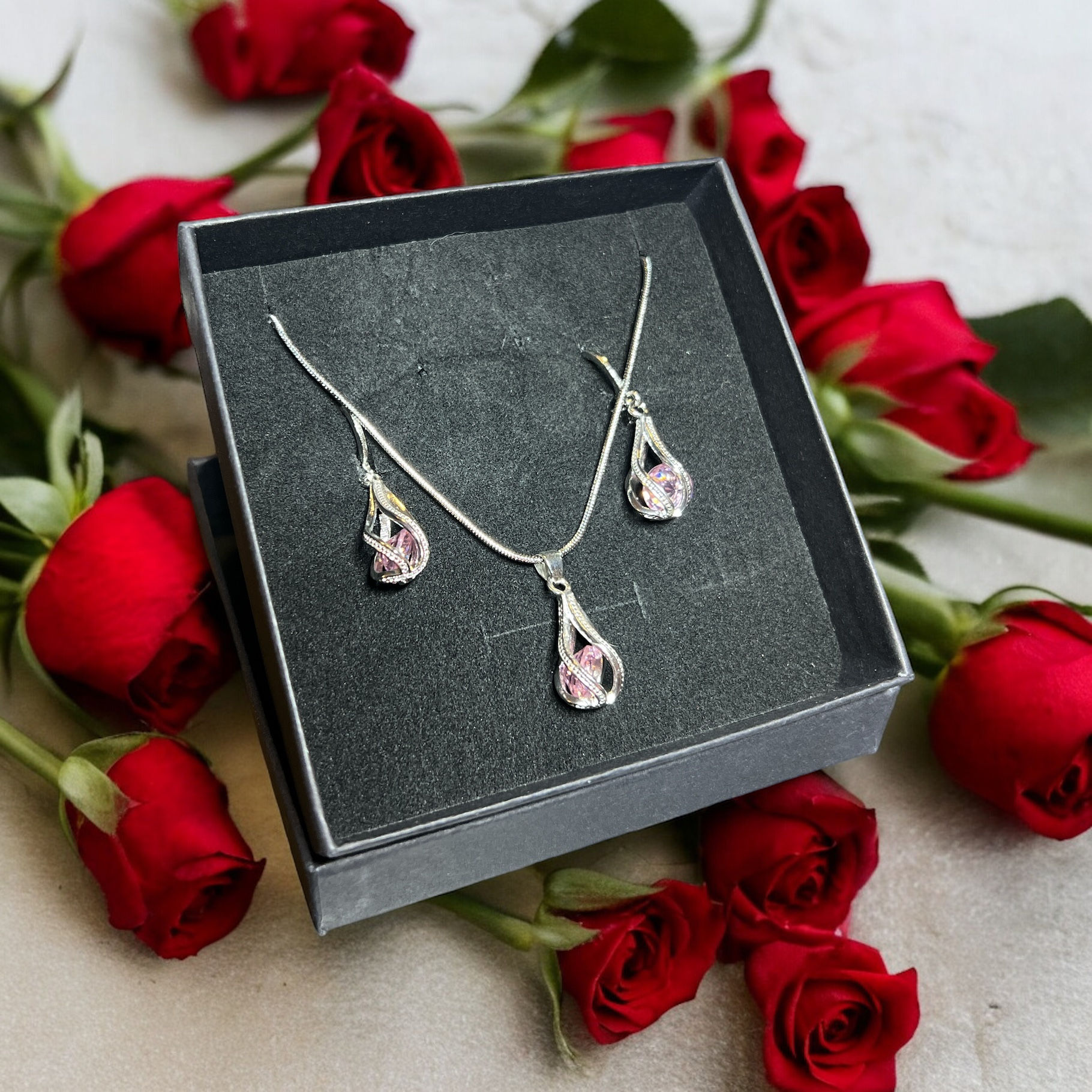 Conjunto de collar y aretes plateados con pedrería rosa y brillantes