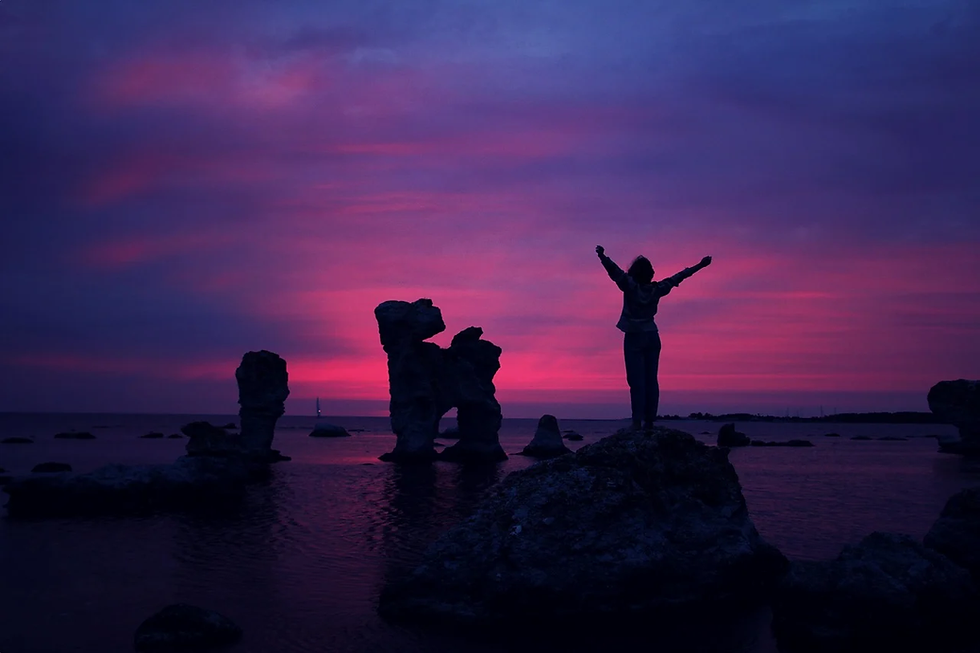 Silhouette of woman stretching at beach during purple sunset