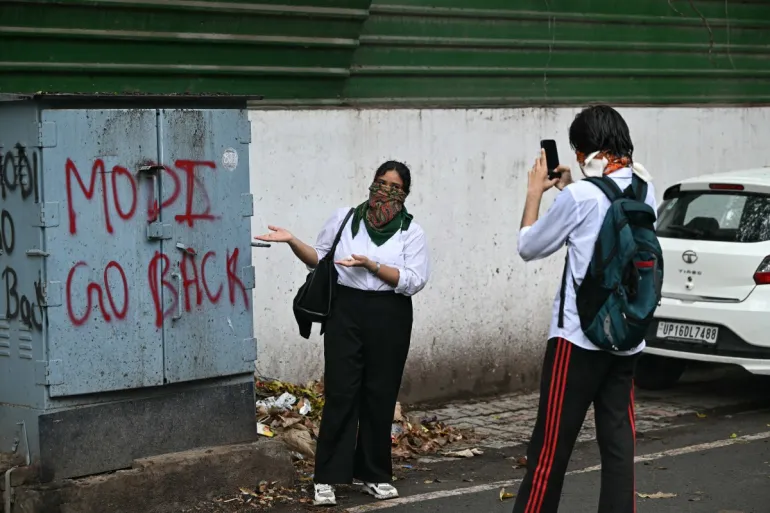 A CJP supporter poses next to a protest message in New Delhi after the police crackdown on July 20, 2026. Credit: Al Jazeera, Sajjad Hussain, AFP