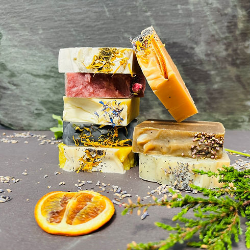 Stacked soaps in various colours with flower petals and dryed botanicals on top of each bar.