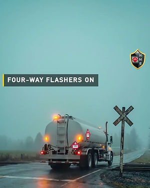 Tank truck with four-way flashers on, stopped at a railroad crossing