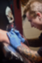 Aiden tattooing a client
